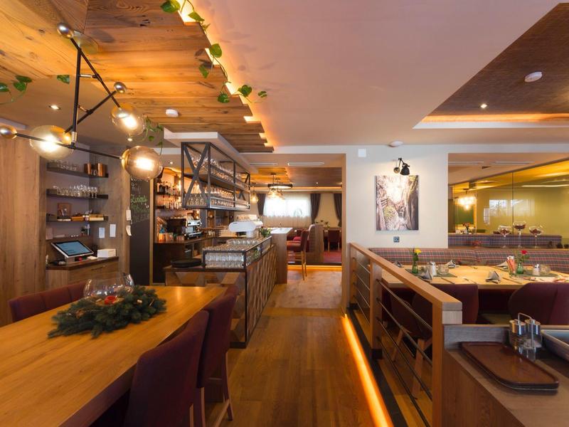 Cozy restaurant with wooden ceiling, warm lighting, and modern seating areas.