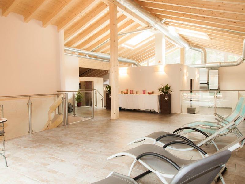 Bright wellness area with lounge chairs and skylights under a wooden beam ceiling.