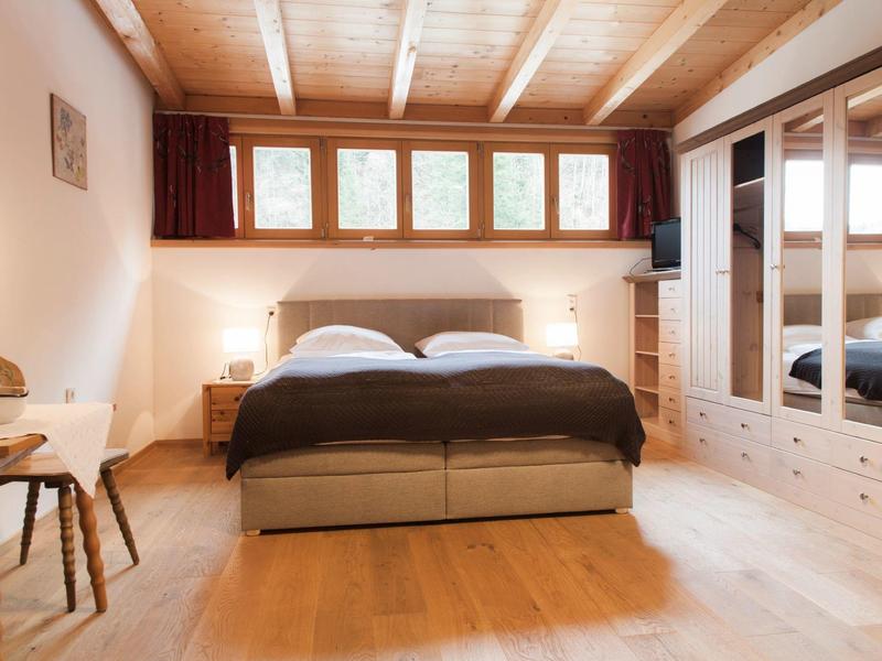 Cozy bedroom with double bed, wooden floor, and mirrored wardrobe system.