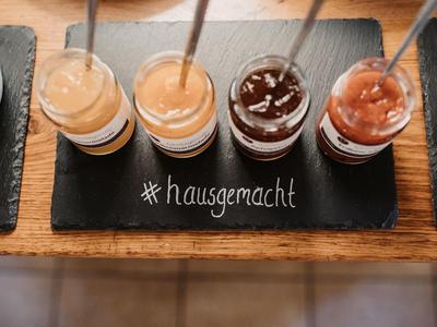 Čtyři malé sklenice s různými domácími džemy na dřevěném prkně.