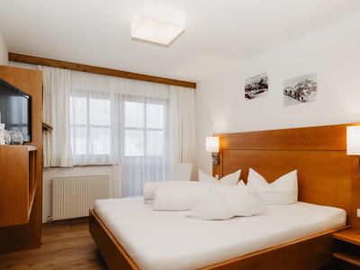 Moderně zařízený hotelový pokoj s velkou postelí, televizí a balkonem