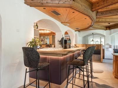 Elegante Bar mit Holzdecke und hohen schwarzen Stühlen in einem Restaurant oder Hotel.