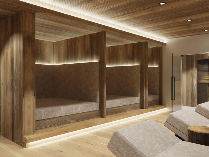 Interiér moderního spa s dřevěnými zdmi, třemi vestavěnými lehátky a pohodlnými křesly.