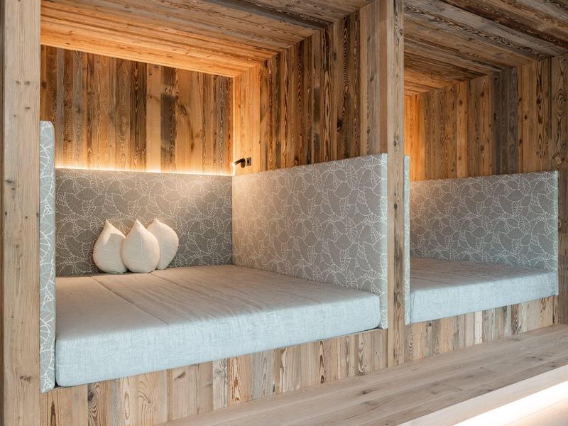 Pohodlný kout s dřevěnými stěnami, čalouněným sedacím prostorem a polštáři v moderním designu.