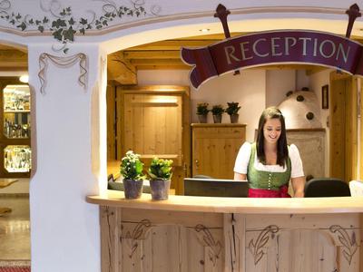 Réception avec une femme en tenue traditionnelle derrière un comptoir en bois dans un cadre chaleureux