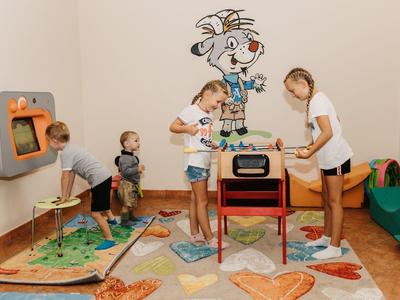 Des enfants jouent à l'intérieur avec divers jouets au mur et au sol.