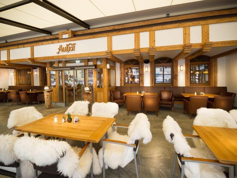 Restaurant avec des tables en bois et des chaises recouvertes de fourrure blanche dans un intérieur confortable.