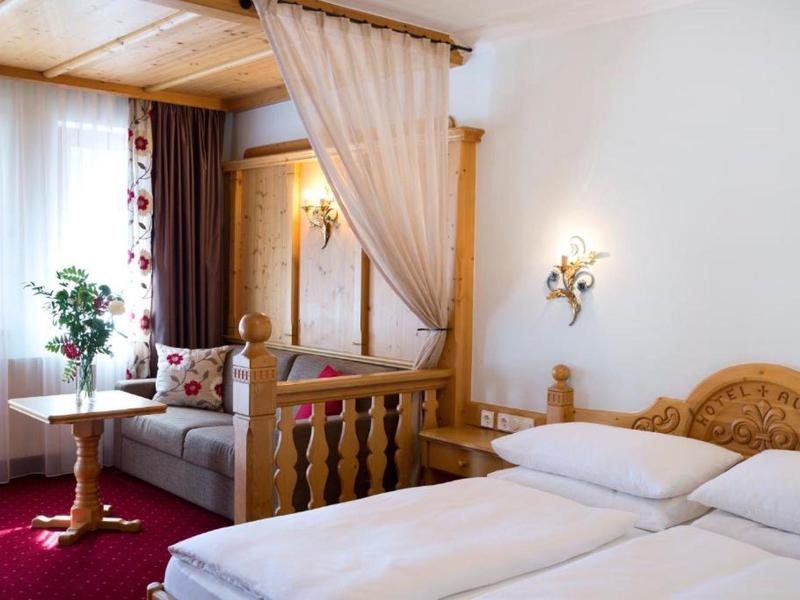 Chambre d'hôtel lumineuse avec lit double, coin salon et moquette rouge.