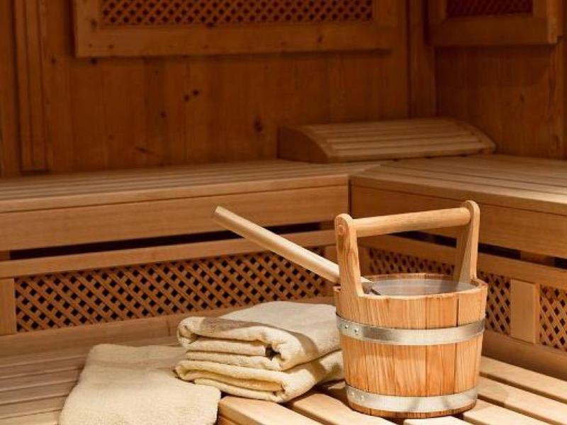 Sauna en bois avec seau, louche et serviettes roulées sur le banc.