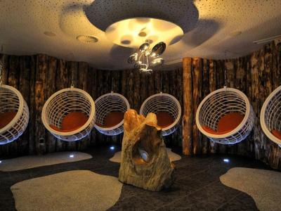 Moderní lounge s kulatými závěsnými křesly a sochařským dřevěným stolem v útulném prostoru