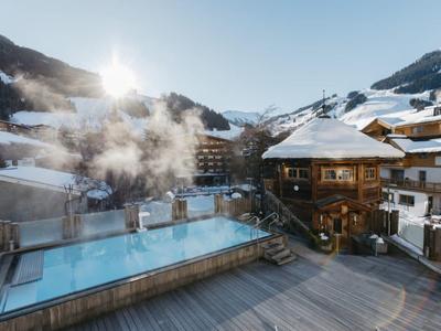 Zimní lázně s vyhřívaným venkovním bazénem v horské krajině za jasného nebe.