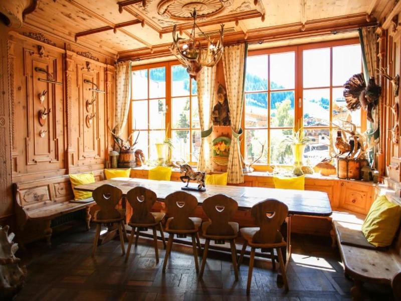 Útulný dřevěný kout s velkým stolem a židlemi, slunečný výhled oknem