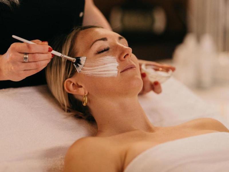 Žena relaxuje během nanášení pleťové masky ve wellness.