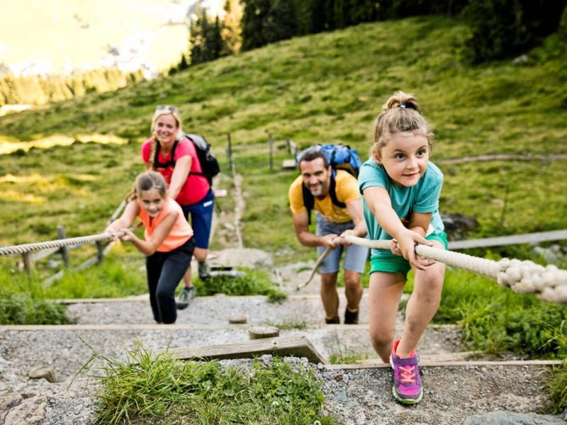 Rodina šplhá po kamenité horské stezce za pomoci lana.
