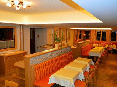 Pohodlná jídelna s oranžovými lavicemi, stoly a měkkým osvětlením.