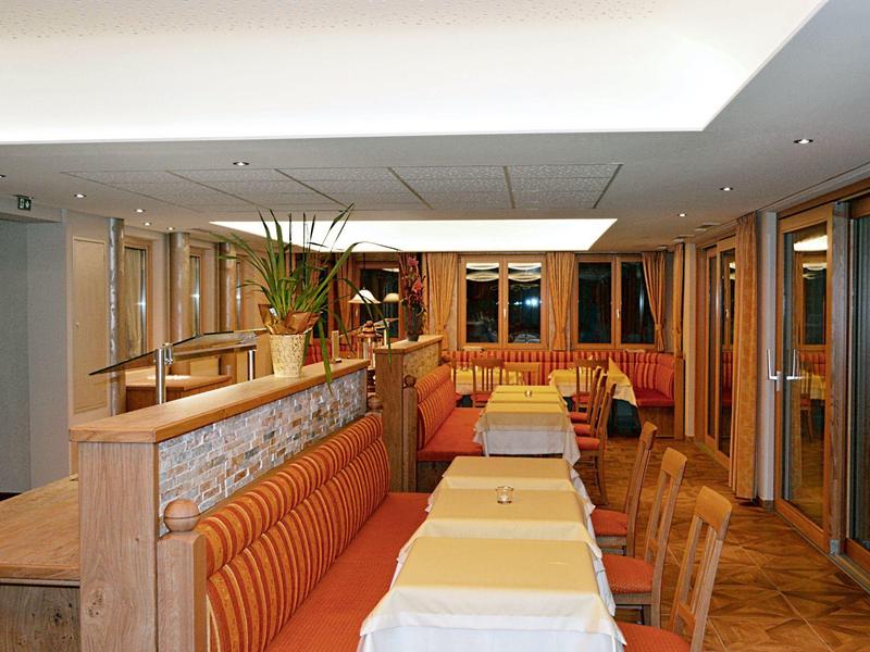 Pohodlný hotelový jídelní kout s dřevěným nábytkem a oranžovými lavicemi.