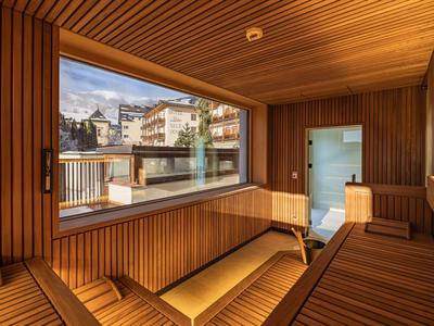 Moderne Sauna mit Holzwänden, großen Fenstern und Blick auf Stadt und Berge.