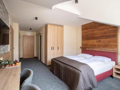 Hotelzimmer mit Doppelbett, Holz- und Steindekor, Schreibtisch, TV und Teppichboden.