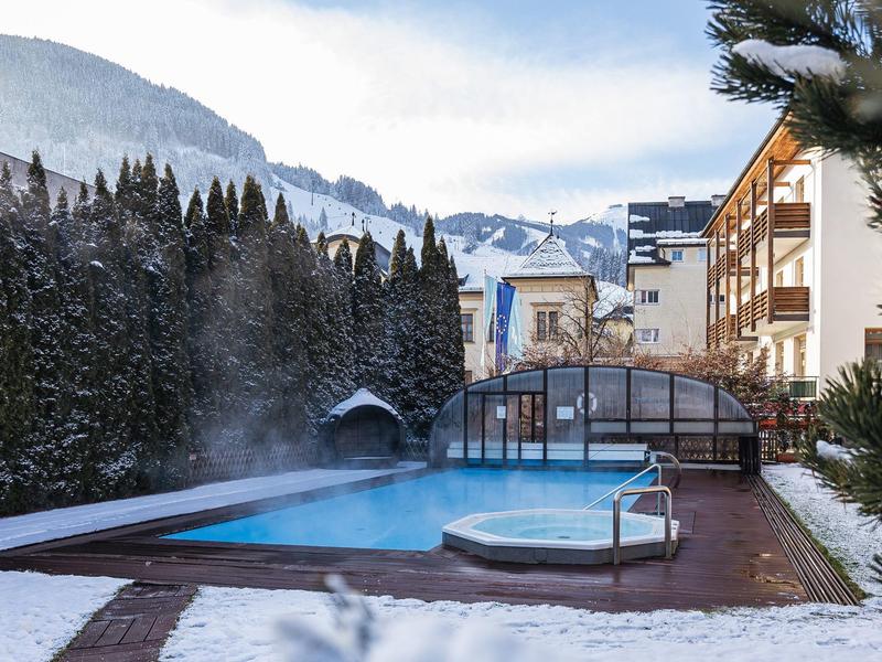 Buitenzwembad met sneeuwbedekking en besneeuwde bergen op de achtergrond