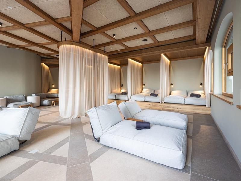 Lichte wellnessruimte met comfortabele ligbedden en houten balkenplafond in een hotel.