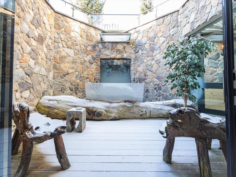 Moderne binnenplaats met stenen muren, houten stoelen en planten in een hotelsfeer.