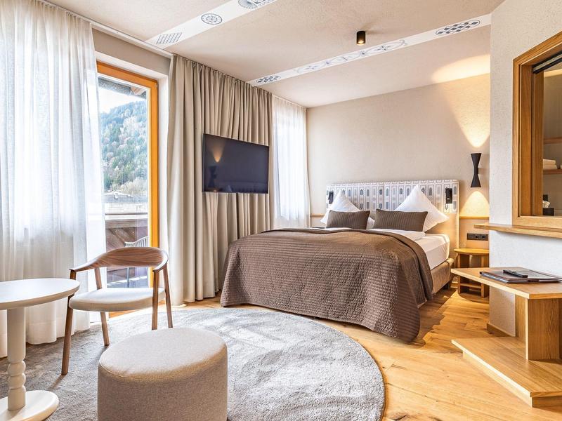 Gezellige hotelkamer met groot bed, zithoek en raam met uitzicht op de bergen.