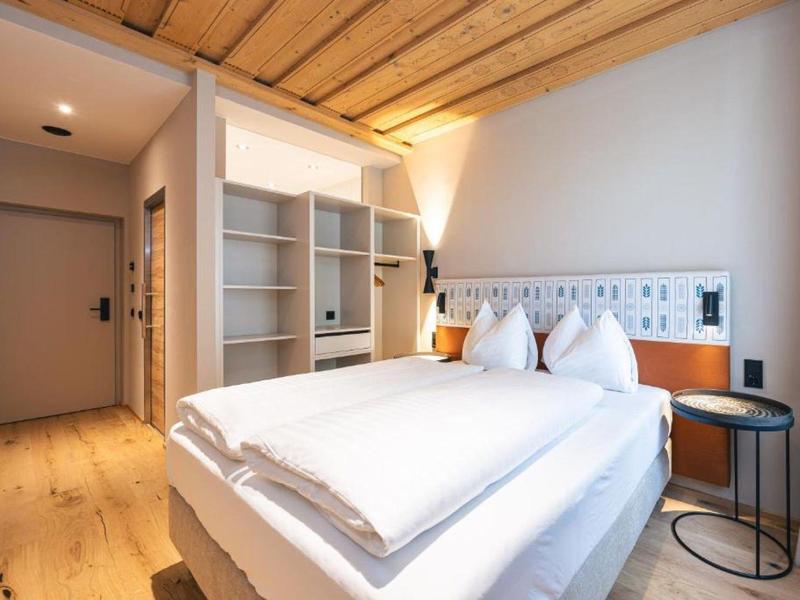 Modern hotelkamer met tweepersoonsbed, houten plafond en minimalistisch ontwerp.