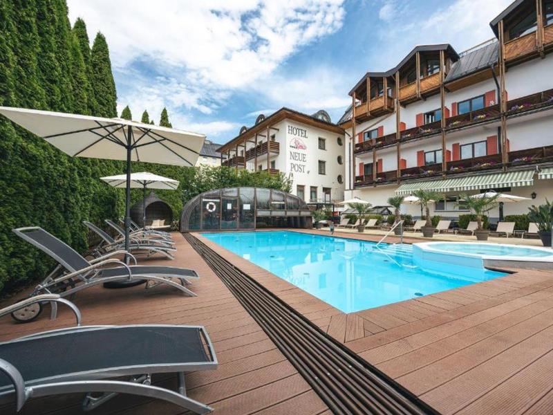Buitenzwembad met ligstoelen en parasols naast een meerverdiepingen hotelgebouw.