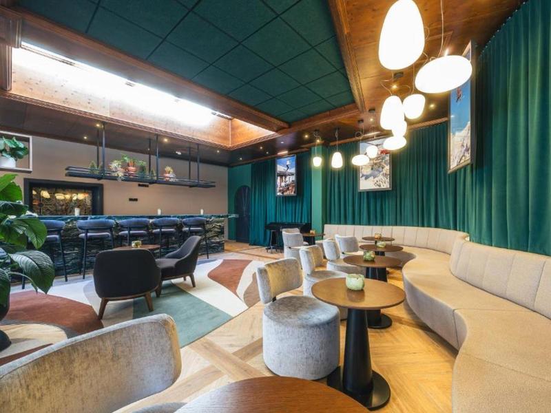 Moderne hotel lobby met gezellige zitplaatsen, tapijten en decoratieve groene gordijnen.