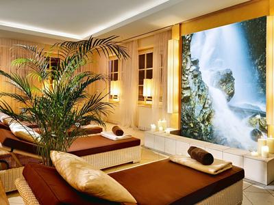 Relaxation room with loungers, pillows, candles, and a large waterfall picture on the wall.
