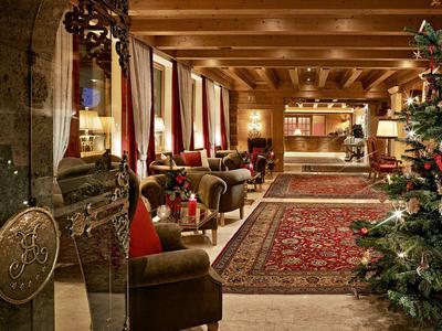 Cozy hotel lobby with armchairs, rugs, and festive Christmas decorations.