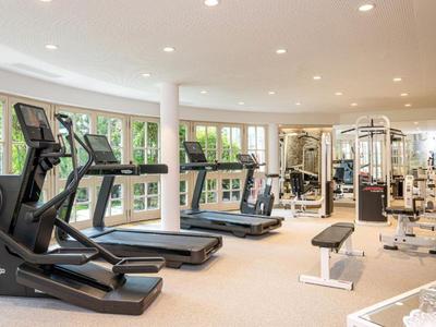 Modern gym with treadmills and strength equipment by large windows.