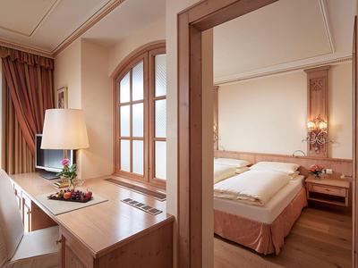 Bright hotel room with desk, chair, and double bed in warm tones.