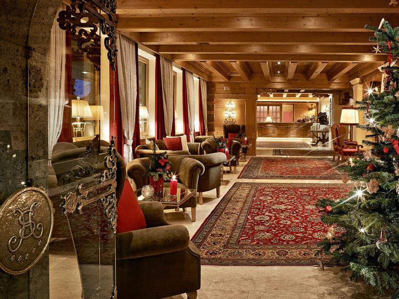 Cozy hotel lobby with Christmas tree, armchairs, and rugs in warm lighting.