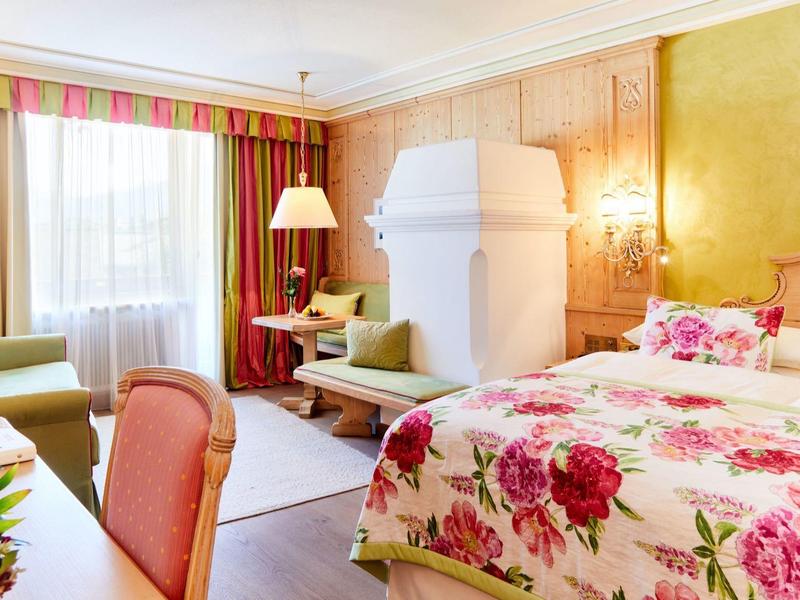 Cozy hotel room with floral bedspread, sofa, and striped curtains.