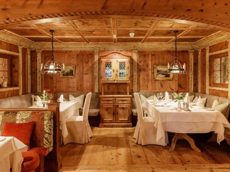 Rustic wooden restaurant with decorated walls and white-covered tables in warm lighting.