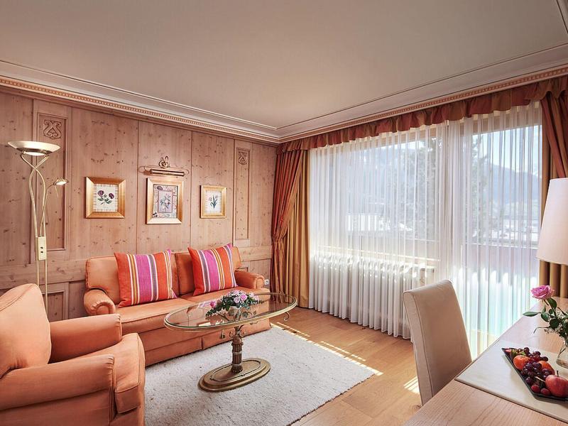 Cozy living room with sofa, armchair, curtains, and view of snowy landscape.