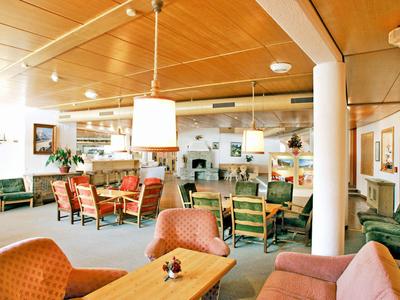 Gemütlicher Hotel-Lounge-Bereich mit Stühlen, Sofas und Holztischen unter Holzdecken.