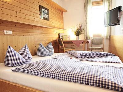 Gemütliches Schlafzimmer mit Holzverkleidung, zwei Betten, karierten Decken und kleinem Schreibtisch.