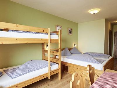 Gemütliches Zimmer mit Holzbett, Etagenbett, Holzmöbeln und grün gestrichener Wand.