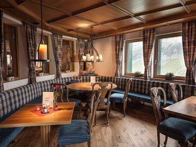 Gemütliches Restaurant mit Holztischen, karierten Polstern und warmem Licht.