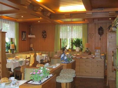 Coin restaurant chaleureux avec murs en bois, tables dressées et fenêtres en baie