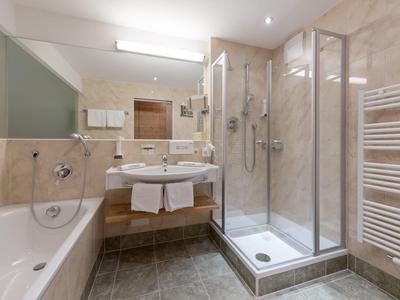 Modernes Badezimmer mit Badewanne, Dusche und Doppelwaschbecken in beige und grauen Tönen.