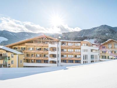 Hotelgebäude in verschneiter Berglandschaft mit klarem Himmel und Sonne.