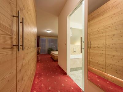 Flur mit rotem Teppich, Holzschränken und Blick ins Badezimmer samt Badewanne und Schlafzimmer.