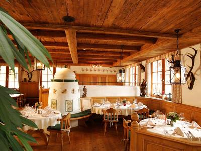 Accogliente sala da pranzo con soffitto di travi in legno, stufa in maiolica e tavoli apparecchiati.
