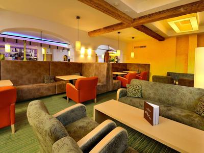 Moderní hotelová lounge s pohodlnými křesly a pohovkami za teplého osvětlení.