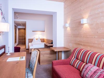 Modern eingerichtetes Wohnzimmer mit rotem Sofa, Holzwänden und Schreibtisch mit Stuhl.