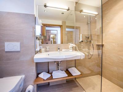 Modernes Badezimmer mit großem Spiegel, Waschtisch und begehbarer Dusche