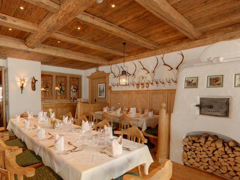 Rustikaler Speiseraum mit Holzdecke, gedecktem Tisch und Kamin mit Holzlager.